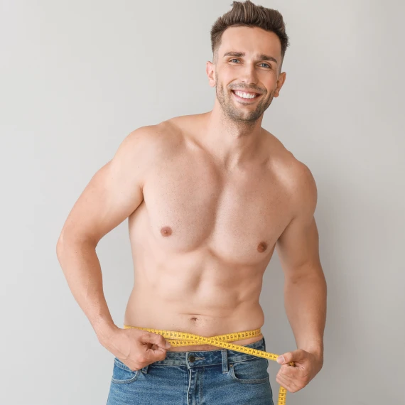 shirtless-man-in-jeans-measures-waist